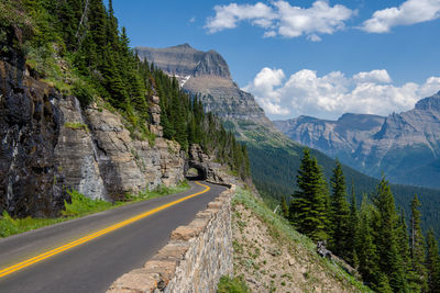 Road amidst trees and mountains against sky