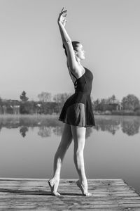 Full length of woman standing on pier over lake against sky