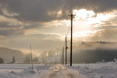 Snow covered landscape against sky during sunset