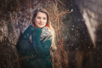 Portrait of smiling young woman in forest during winter