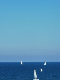 Sailboat in sea against clear blue sky