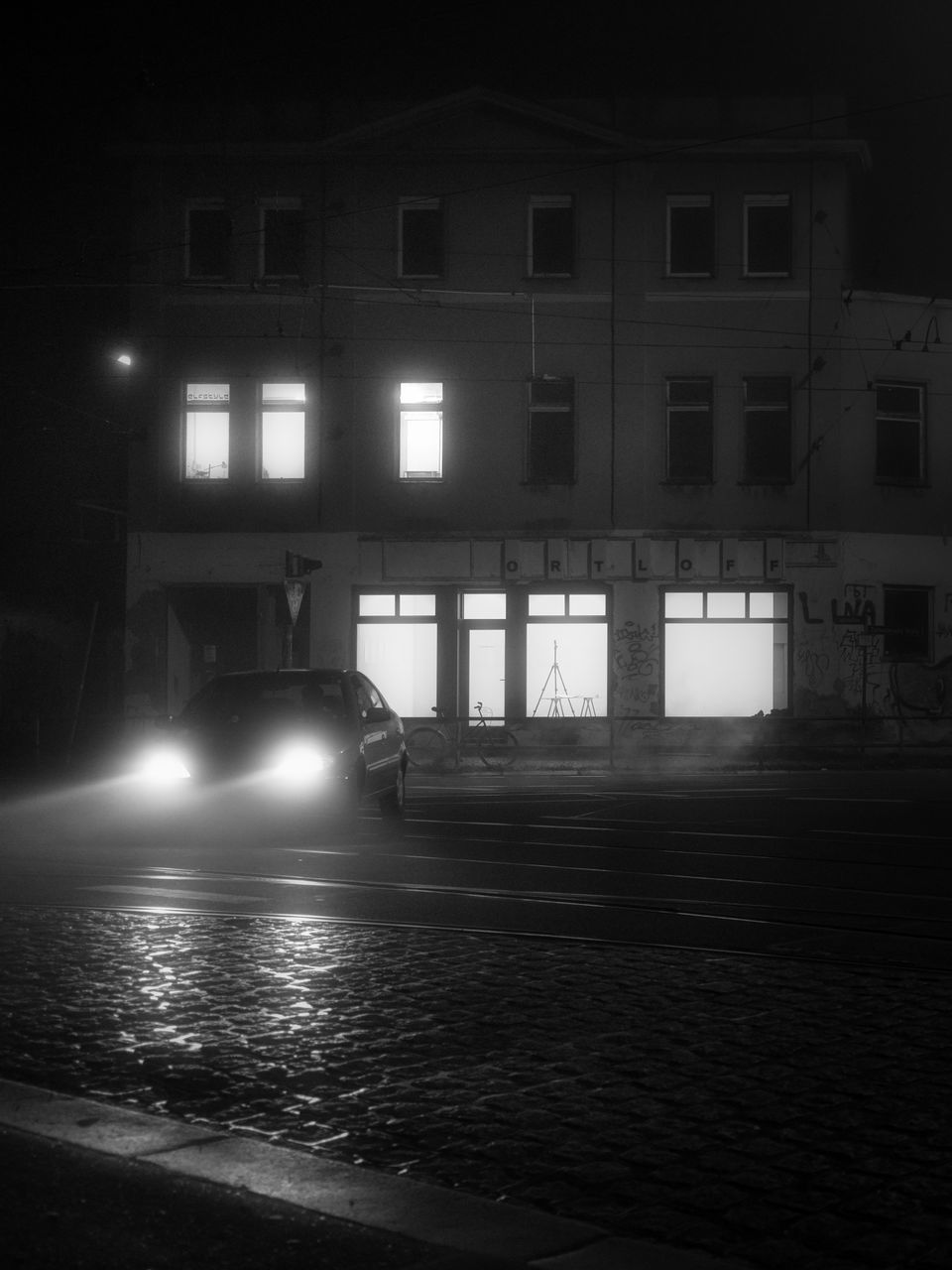 ILLUMINATED STREET LIGHT BY BUILDING AT NIGHT