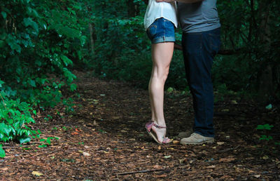 Low section of couple standing in forest