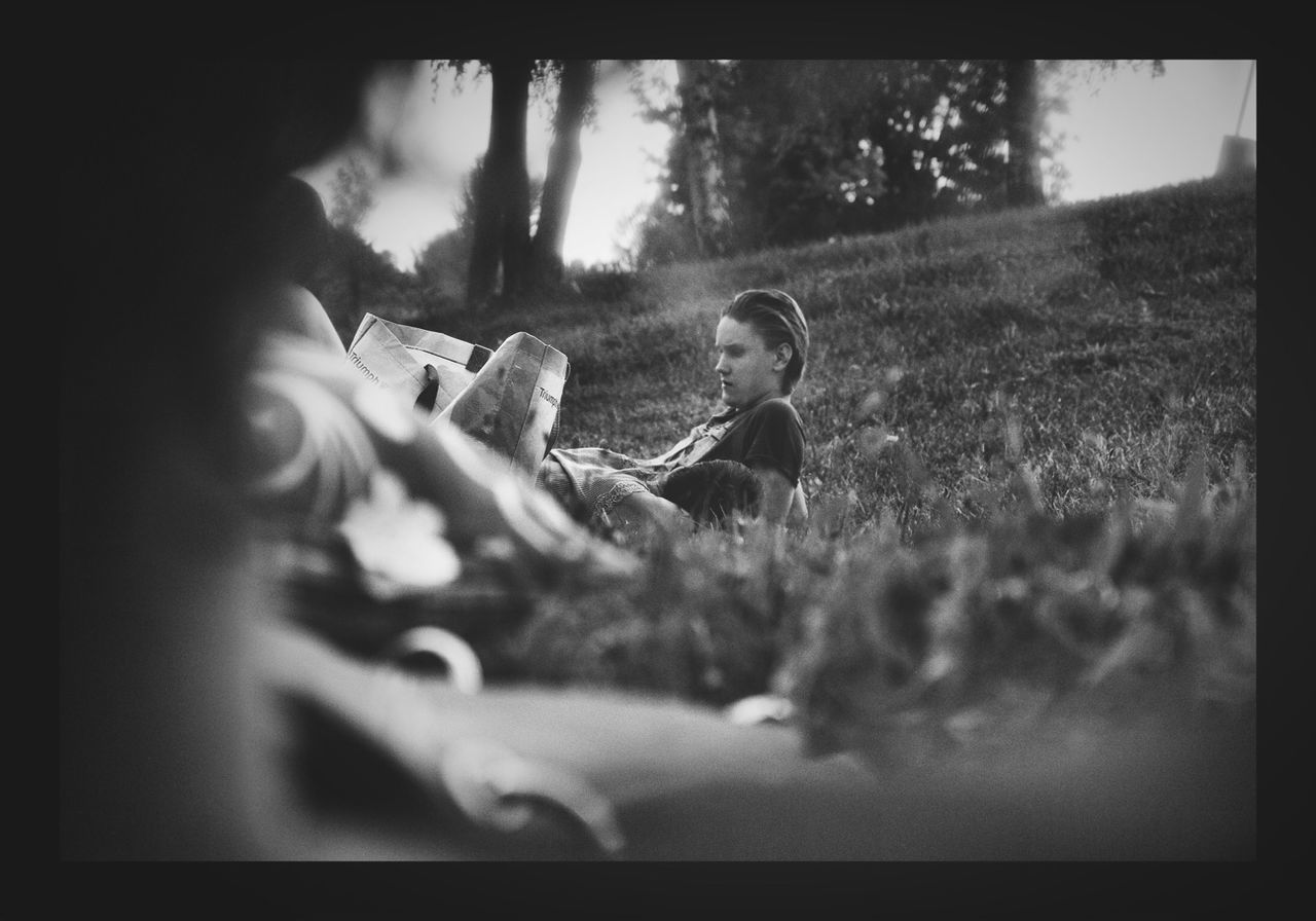 lifestyles, transfer print, leisure activity, auto post production filter, holding, men, selective focus, person, field, childhood, sitting, playing, tree, boys, focus on foreground, casual clothing