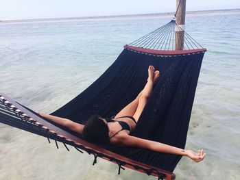 Woman relaxing on hammock by sea