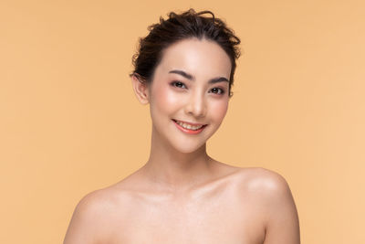 Portrait of smiling young woman against gray background