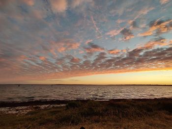 Scenic view of sea against dramatic sky during sunset