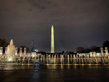 Fountain in city against sky at night