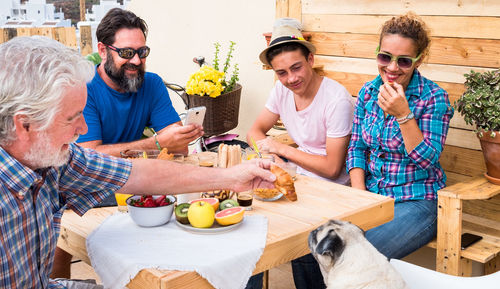 Happy family feeding pug during breakfast at building terrace