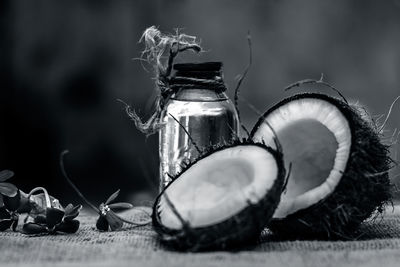 Close-up of halved coconut with bottle on table