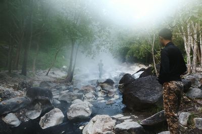 Man looking at waterfall in forest