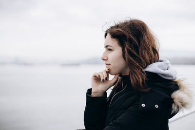 Pensive young girl looking to sea from boat. teenager girl at ferryboat. cold grey sea