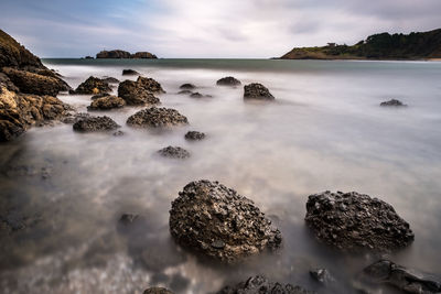 Scenic view of rocks in sea against sky