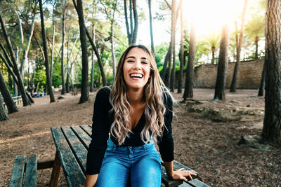 Portrait of cheerful young woman sitting on table