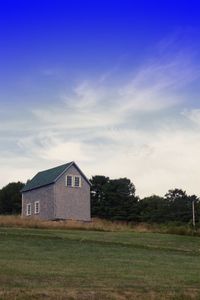 Houses on field against cloudy sky