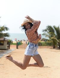 Side view of woman jumping at beach