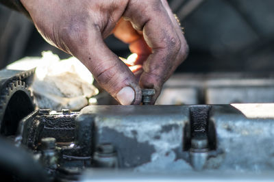 Cropped hand of mechanic working on engine of car