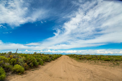 Road amidst field against sky