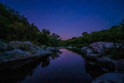 Reflection of trees in lake at night