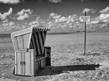 Hooded beach chair on beach against sky