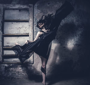 Young woman dancing against wall