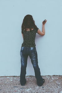 Full length of woman standing against wall