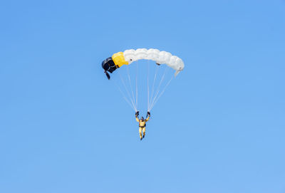 Low angle view of person paragliding against clear blue sky