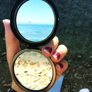 Close-up of woman holding sunglasses against sky