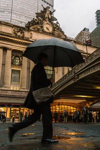 Low angle view of man standing on bridge in city