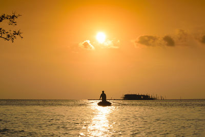 Silhouette person on sea against sky during sunset