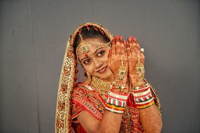 Close-up of smiling young bride gesturing against wall at home