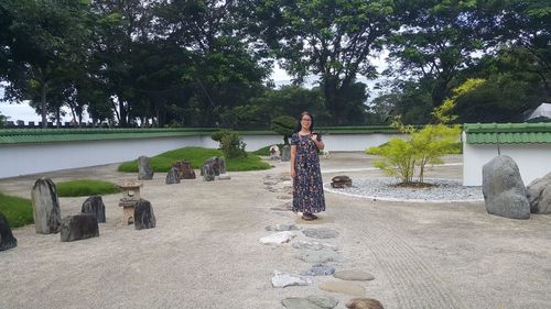 Woman standing on rock against trees