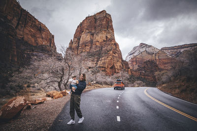 People on road amidst rocky mountains against sky