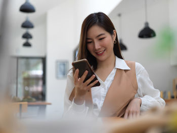 Smiling businesswoman using phone at office