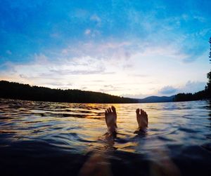 Low section of person relaxing in water at sunset