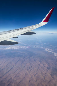 Airplane wing flying over blue sky