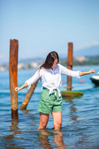 Woman standing in water at beach against sky