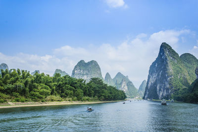 Scenic view of sea by mountains against sky