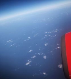 Aerial view of airplane wing over sea against blue sky