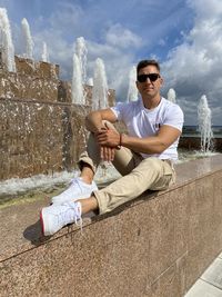 Young man sitting on wall