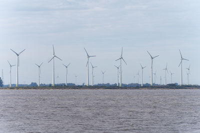 Wind turbines on field against sky