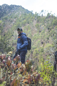 Hipster young boy with backpack enjoying trekking sunset on the mountains. tourist traveler.