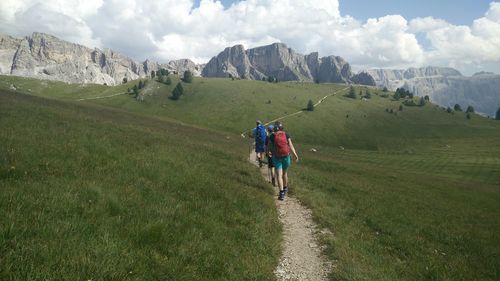 Rear view of people walking on mountain against sky