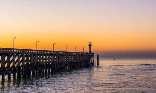 Pier over sea against sky during sunset