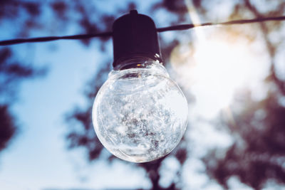 Low angle view of light bulb hanging against sky