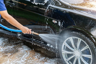 The washing process on a self service car wash high pressor spray water on wheel.