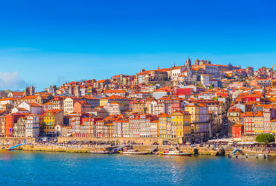 Townscape by sea against clear blue sky