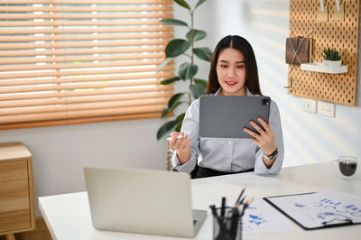 Portrait of young woman using digital tablet while sitting at home