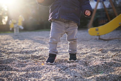 Low section of baby standing on land in park