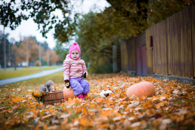 Rear view of girl sitting on autumn leaves